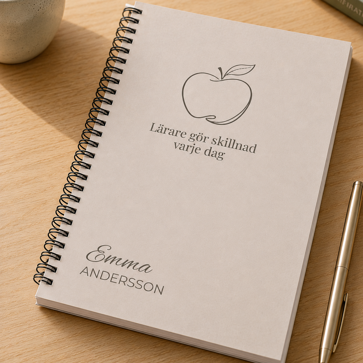 Närbild på personlig beige anteckningsbok med namnet Emma Andersson och äppelmotiv